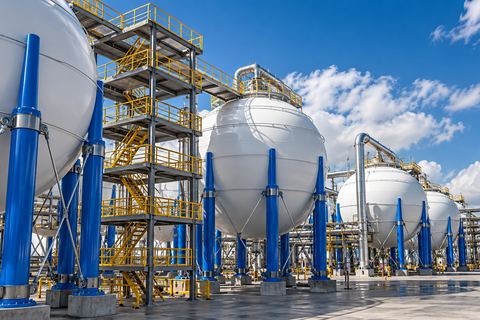 Large white spherical storage tanks on blue steel supports at an industrial gas site